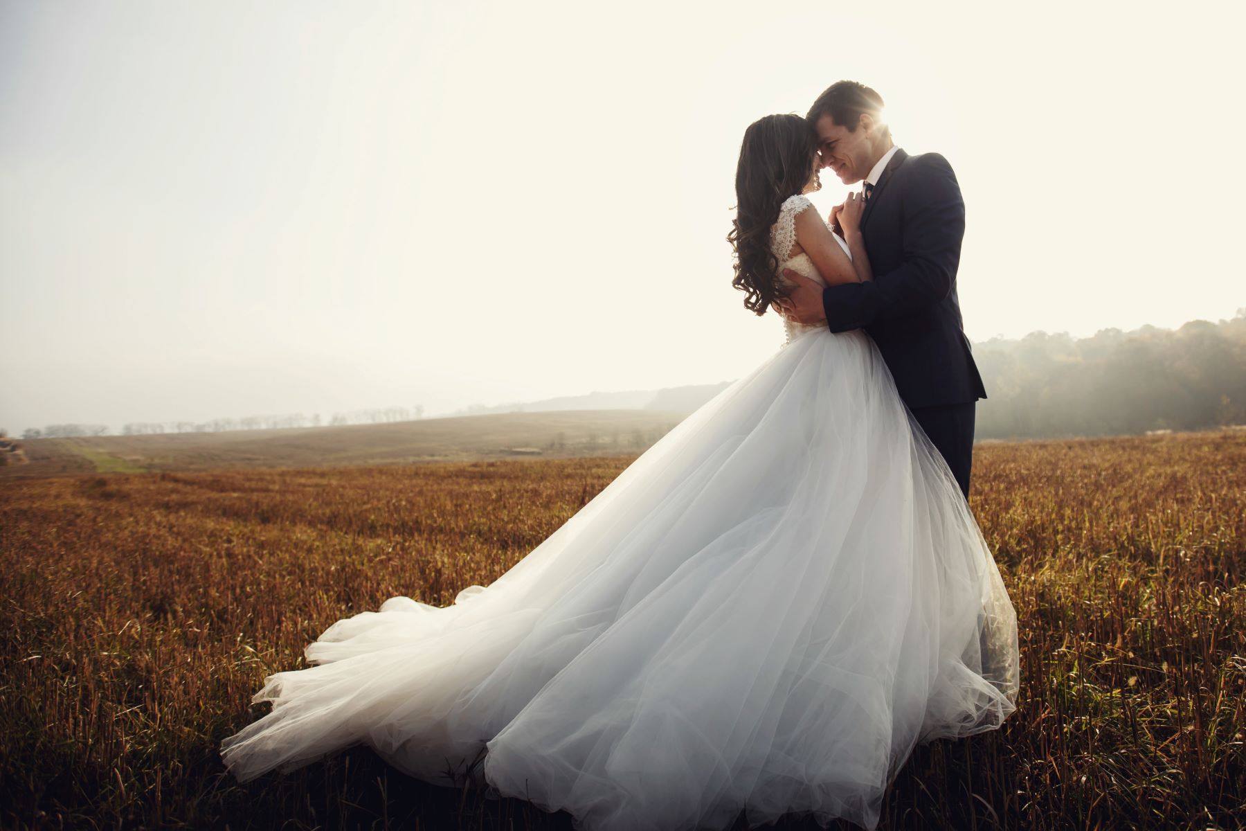 Bride and groom in field embracing